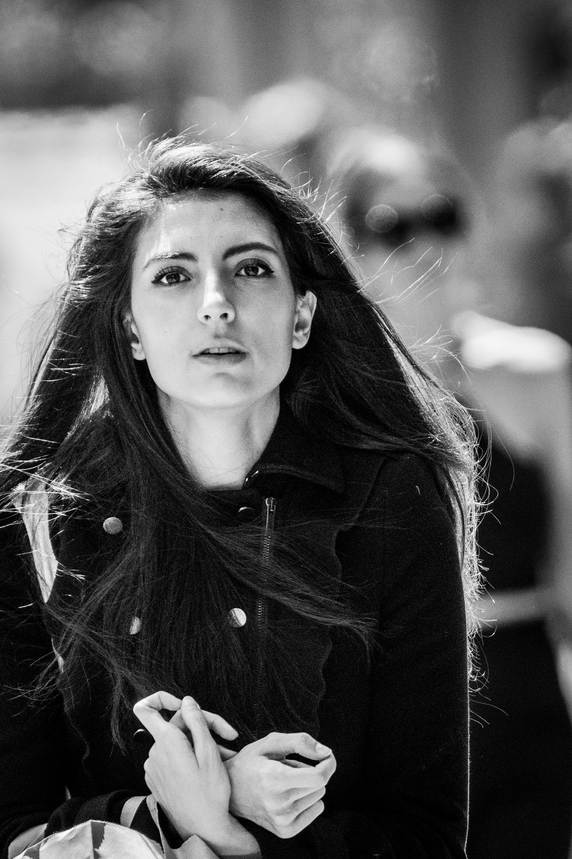 Portrait d'une jeune femme, cheveux au vent, mains jointes